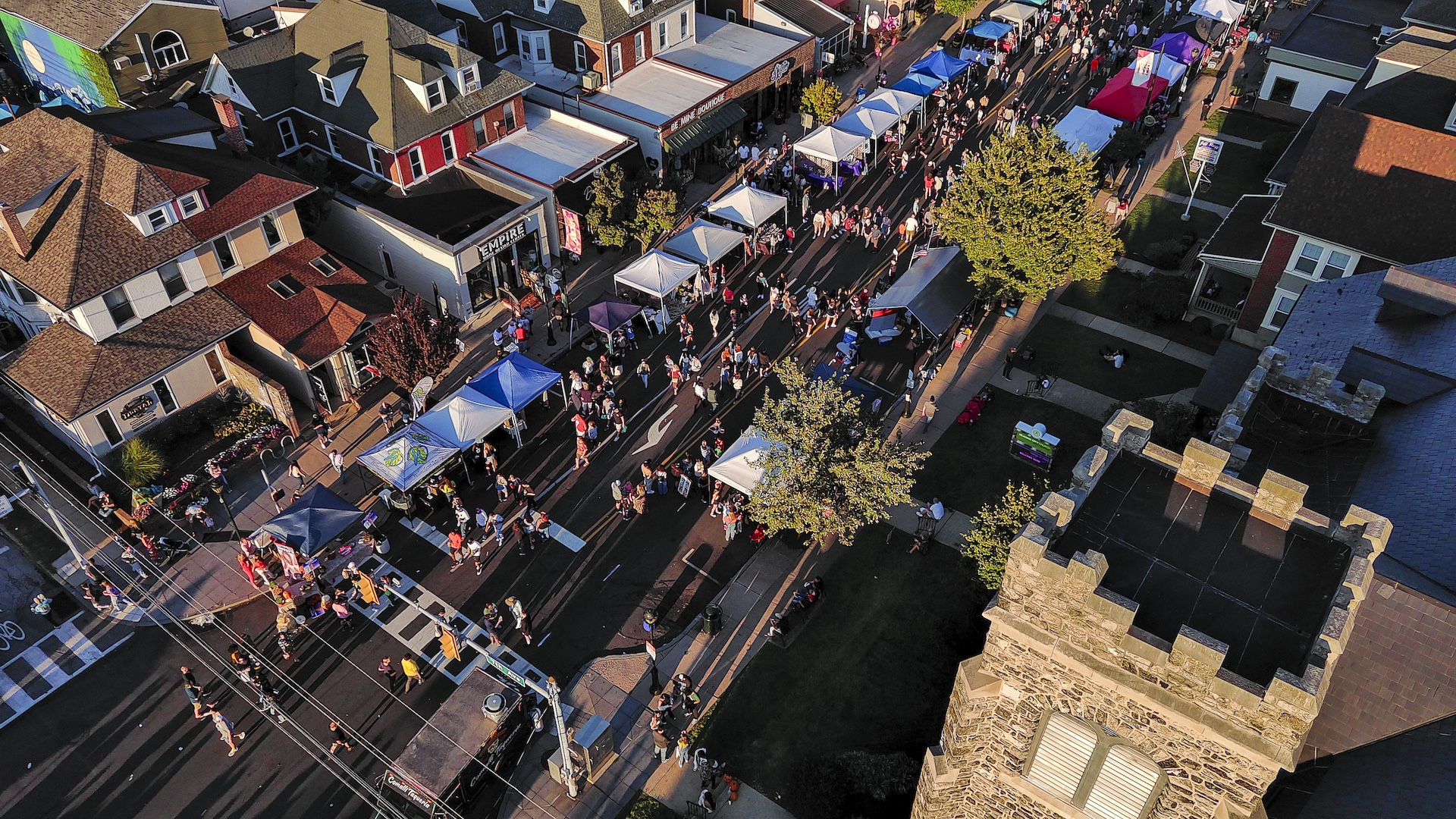 Colorful houses and tents along Festival street in small town. Reading City Church towers on foreground, drone view