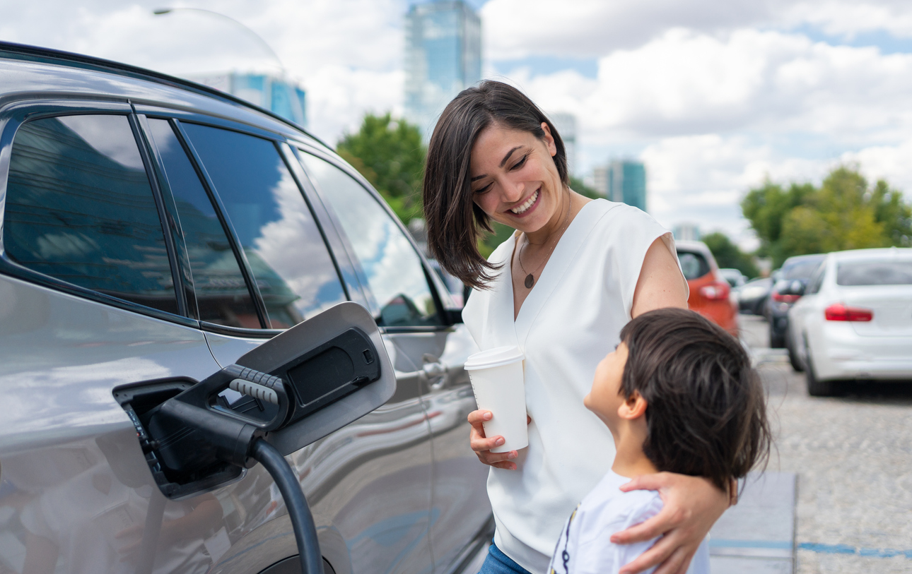 A woman and her child charging their electric vehicle at a charging station.