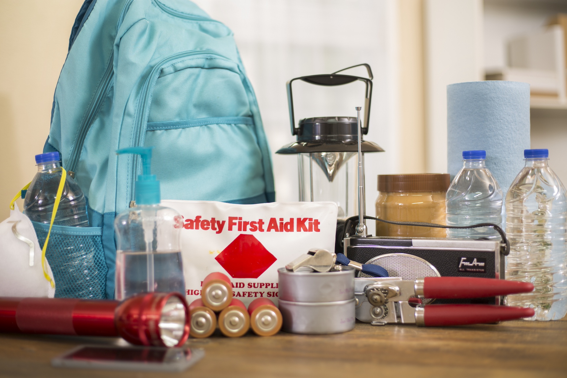 Emergency preparedness supplies. A large collection of supplies to be used in case of a natural disaster (hurricane, flood, earthquake, etc) including flashlight, backpack, batteries, water bottles, first aid kit, lantern, radio, can opener and mask. No People.