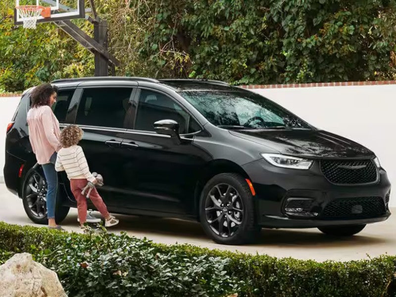 Mother opening the door of her 2026 Chrysler Pacifica to help her daughter in